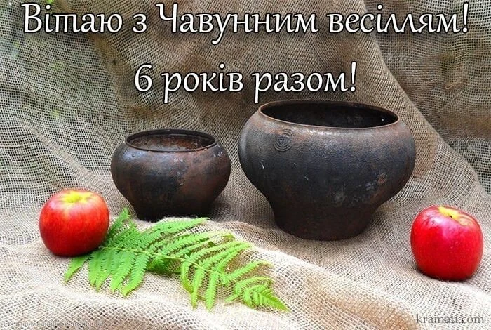 Два чавунові горщики з яблуками та папороттю на льоні.