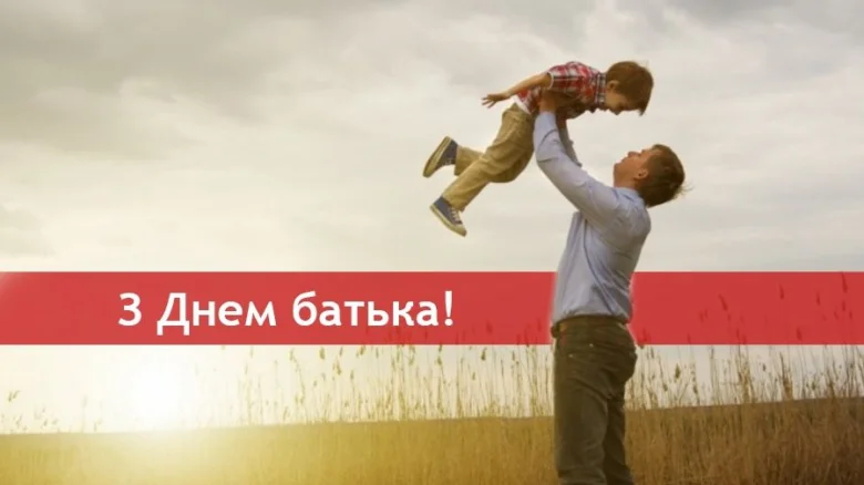 Тато піднімає сина вгору на фоні поля.