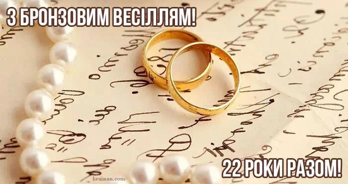 Золоті кільця та перлини на фоні рукопису для бронзового весілля.