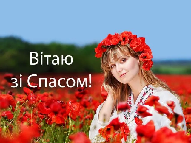 Жінка в вінку з маків у полі квітів вітає зі Спасом.