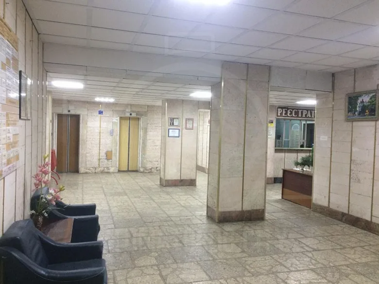 Внутрішній вигляд коридору стоматологічної поліклініки з ліфтами та рецепцією.